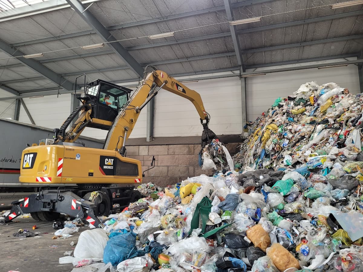 Excavator sorting waste at an indoor recycling facility